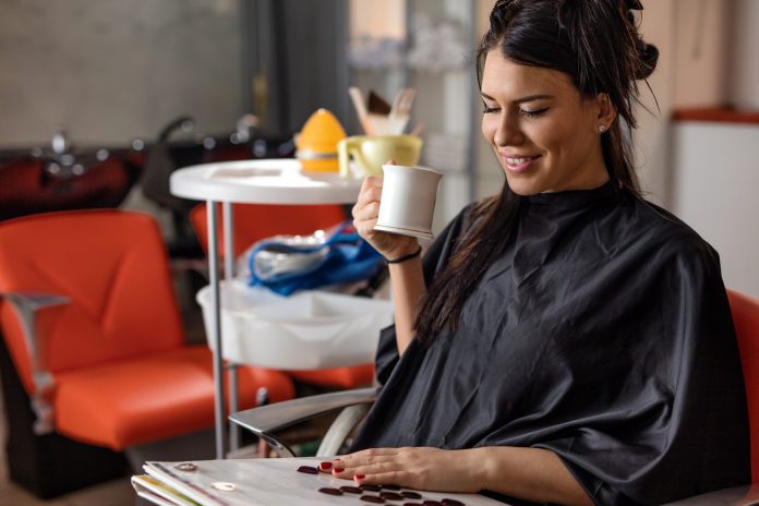 Smiling woman at hairdresser's looking at hair color palette.